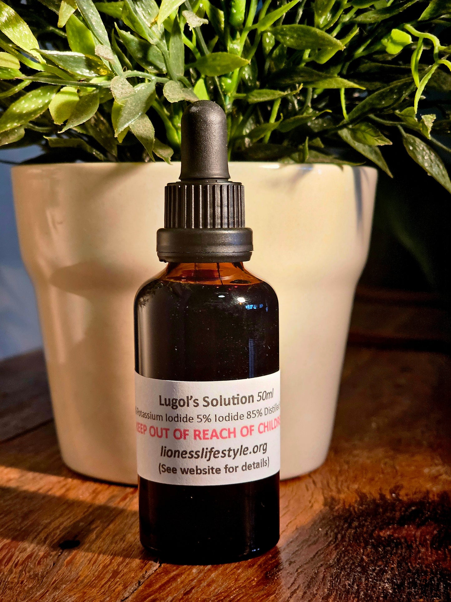 Lugol’s Solution 50ml iodine supplement in amber dropper bottle placed on rustic wooden table with green plant in background – lionesslifestyle.org natural wellness product"