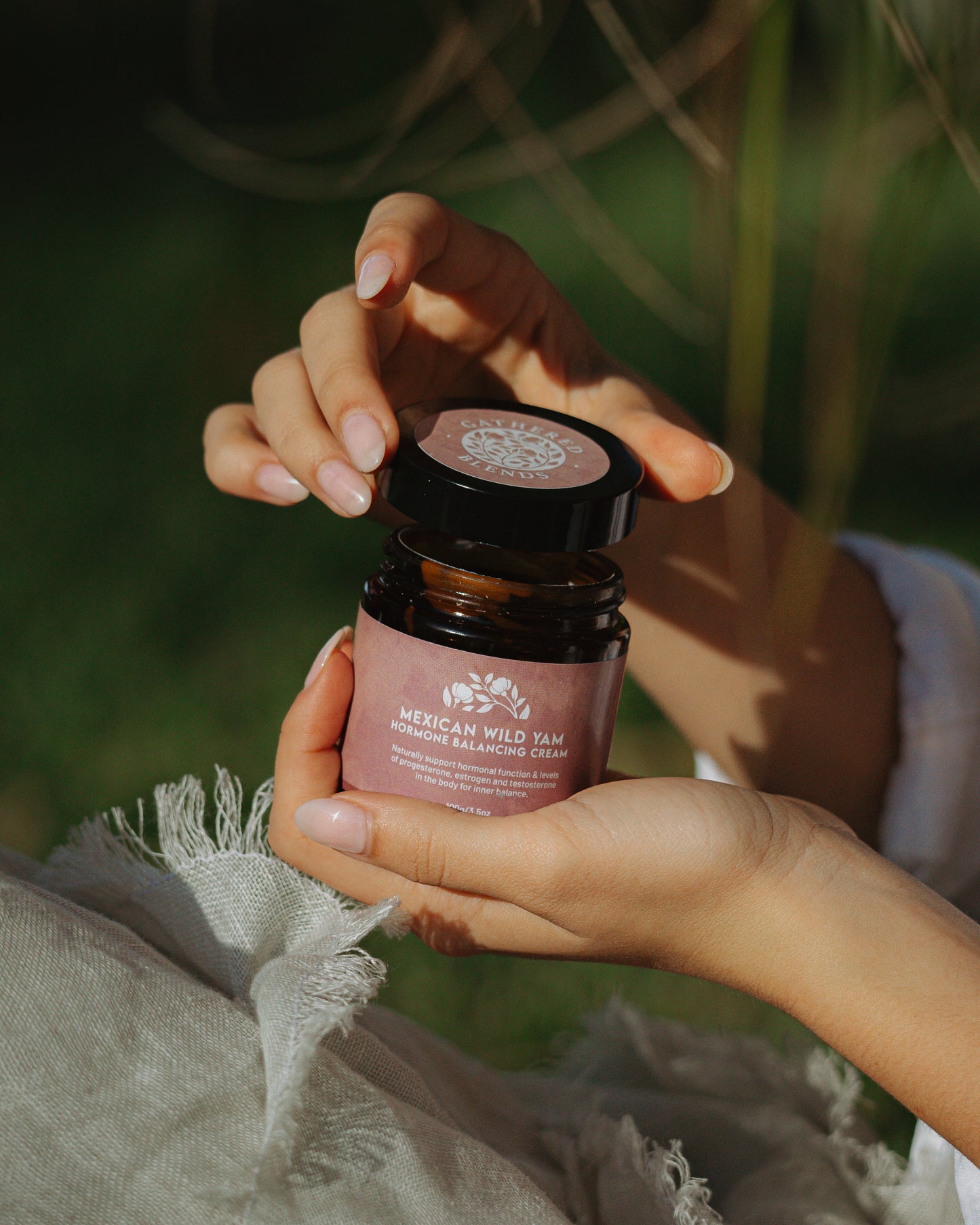 Woman holding jar of Mexican Wild Yam Hormone Balancing Cream in natural outdoor setting – natural progesterone support for hormonal balance and wellness