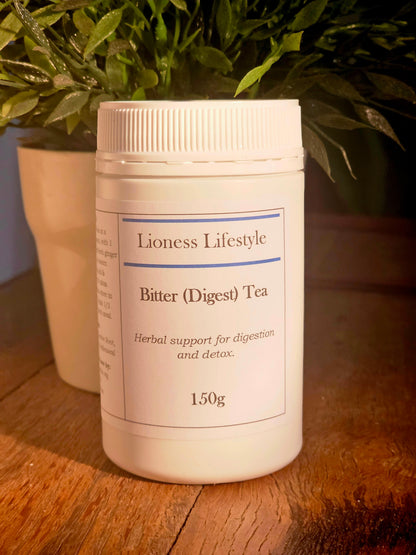 Lioness Lifestyle Bitter Digest Tea 150g container for herbal digestion and detox support, natural supplement on rustic wood table with indoor plant decor